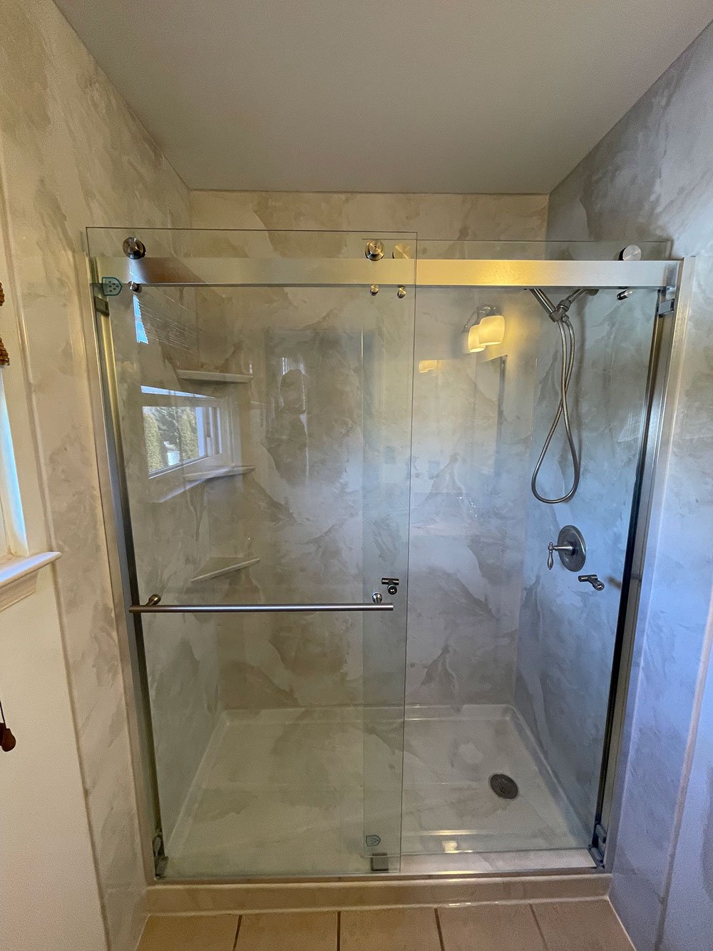 This is a tub-to-shower conversion in our acrylic system. The shower base is the same color as the walls which is silver/white marble. Finished off with a beautiful 74